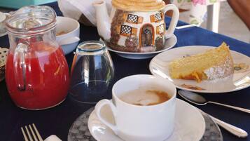 Una mesa con una tetera, una jarrón, una taza de café, un plato con una porción de pastel y una cuchara.
