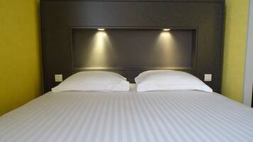 Une chambre d’hôtel avec un grand lit, deux oreillers et une tête de lit dotée d’un éclairage intégré.