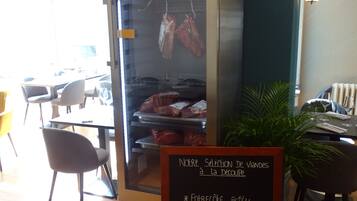 A restaurant interior with a meat display case and a chalkboard menu.