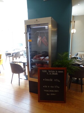 A restaurant interior with a meat display case and a chalkboard menu.