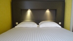 Une chambre d’hôtel avec un grand lit, deux oreillers et une tête de lit dotée d’un éclairage intégré.