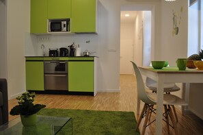 A compact kitchen with green cabinets, a microwave, and a dining area with a table and chairs.