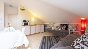 Un espacio habitable compacto con kitchenette, comedor y sofá.