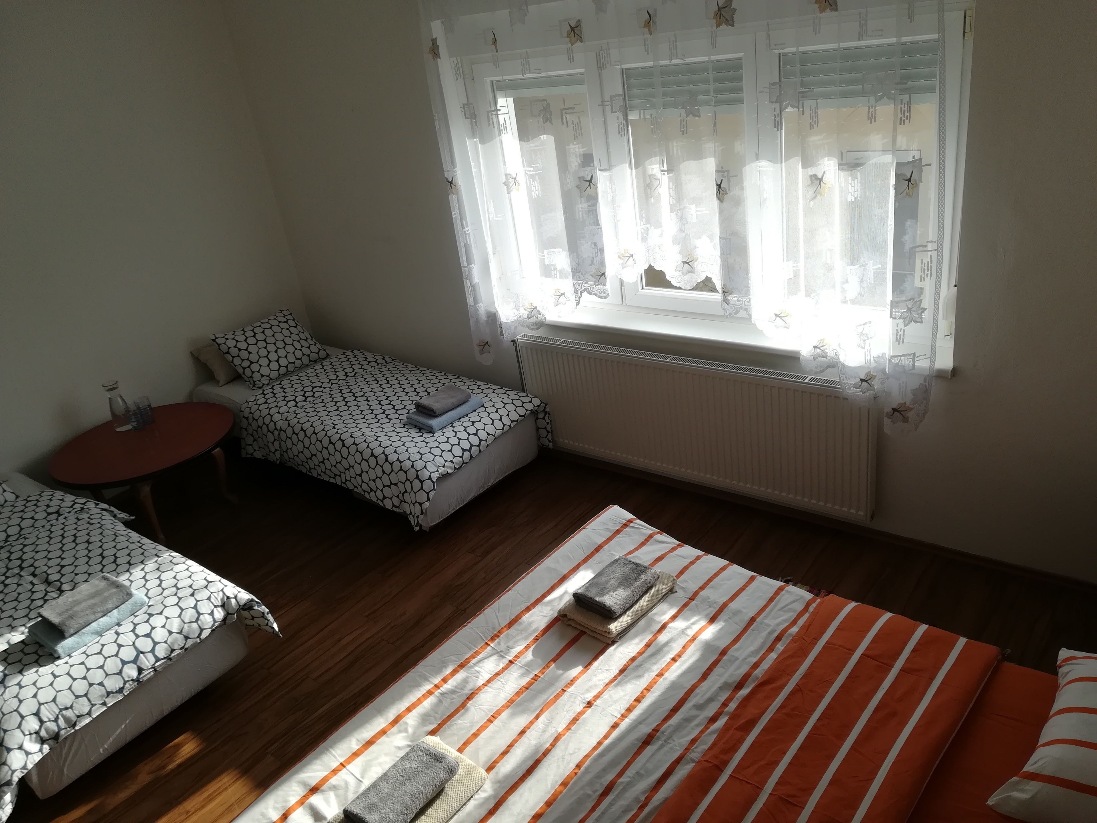 A room with a bed, a small table, and a window with curtains.