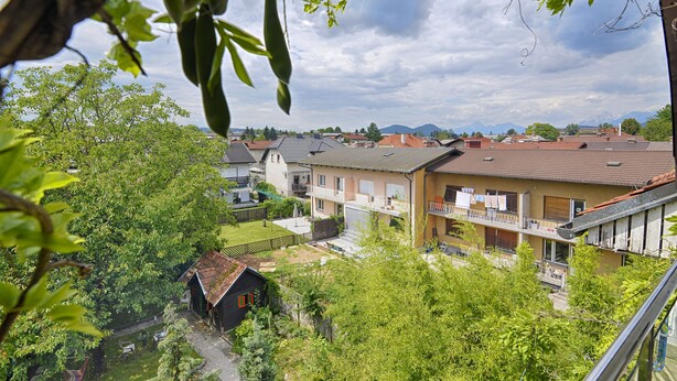 Un barrio residencial con casas, un pequeño jardín y vistas a montañas a lo lejos.