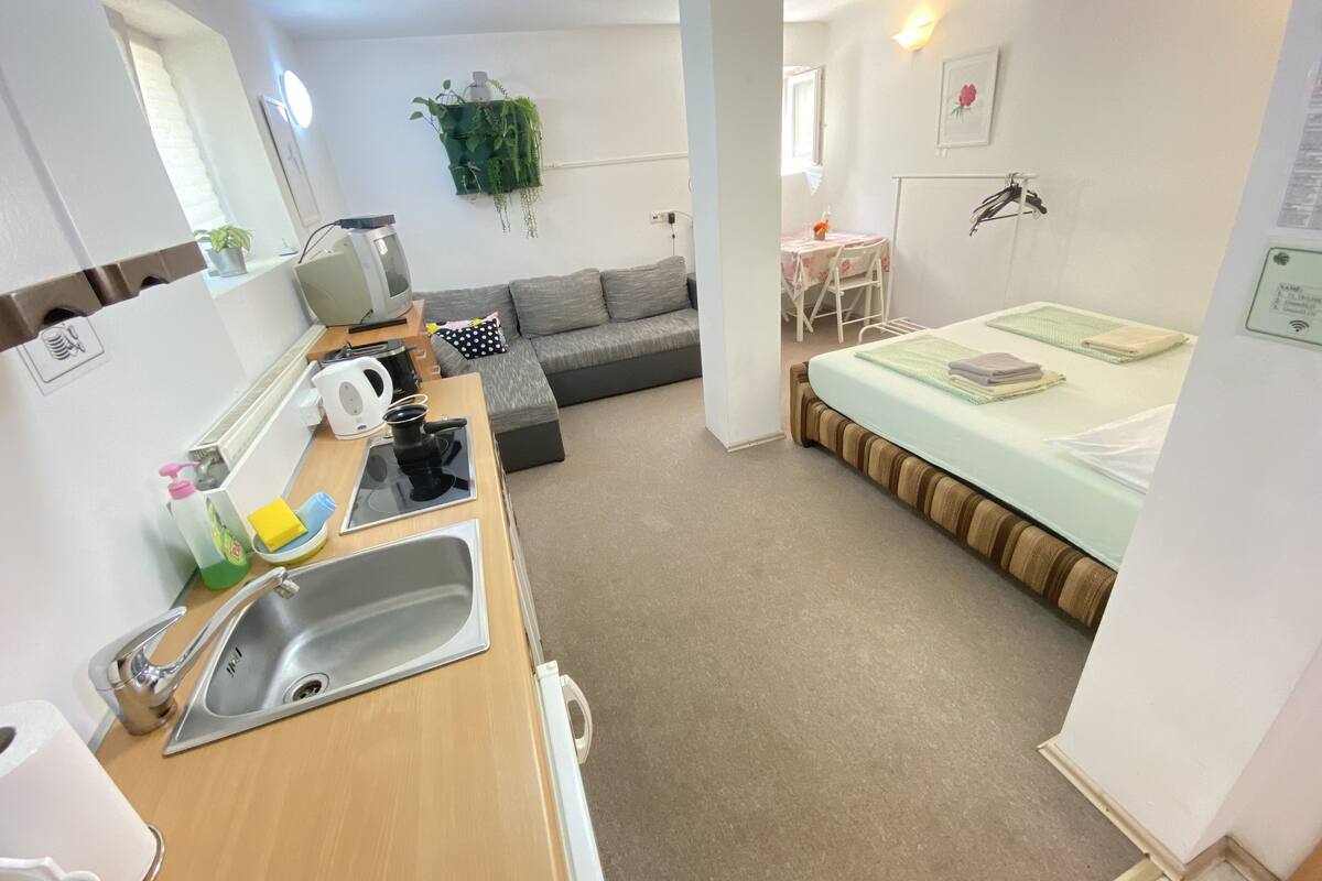 Une pièce compacte comprenant un coin cuisine, un lit, un canapé et une petite table.