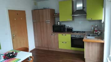 Une cuisine de taille réduite, dotée de meubles en bois, d’un four à micro-ondes, d’une cuisinière et d’un évier.