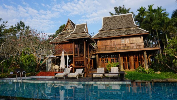 A wooden house with a pool and lounge chairs. - Baansuwanburi (San Sai)