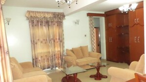 Una sala de estar con sofás color crema, una mesa de centro de vidrio y armarios de madera.