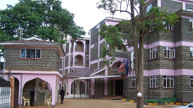 Un hotel con un patio central, varios pisos y una fachada combinada de ladrillo y color rosa.