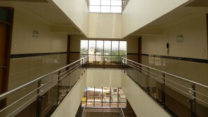 Ein mehrgeschossiges Interieur mit einer zentralen Treppe, Glasgeländern und Blick ins Freie.