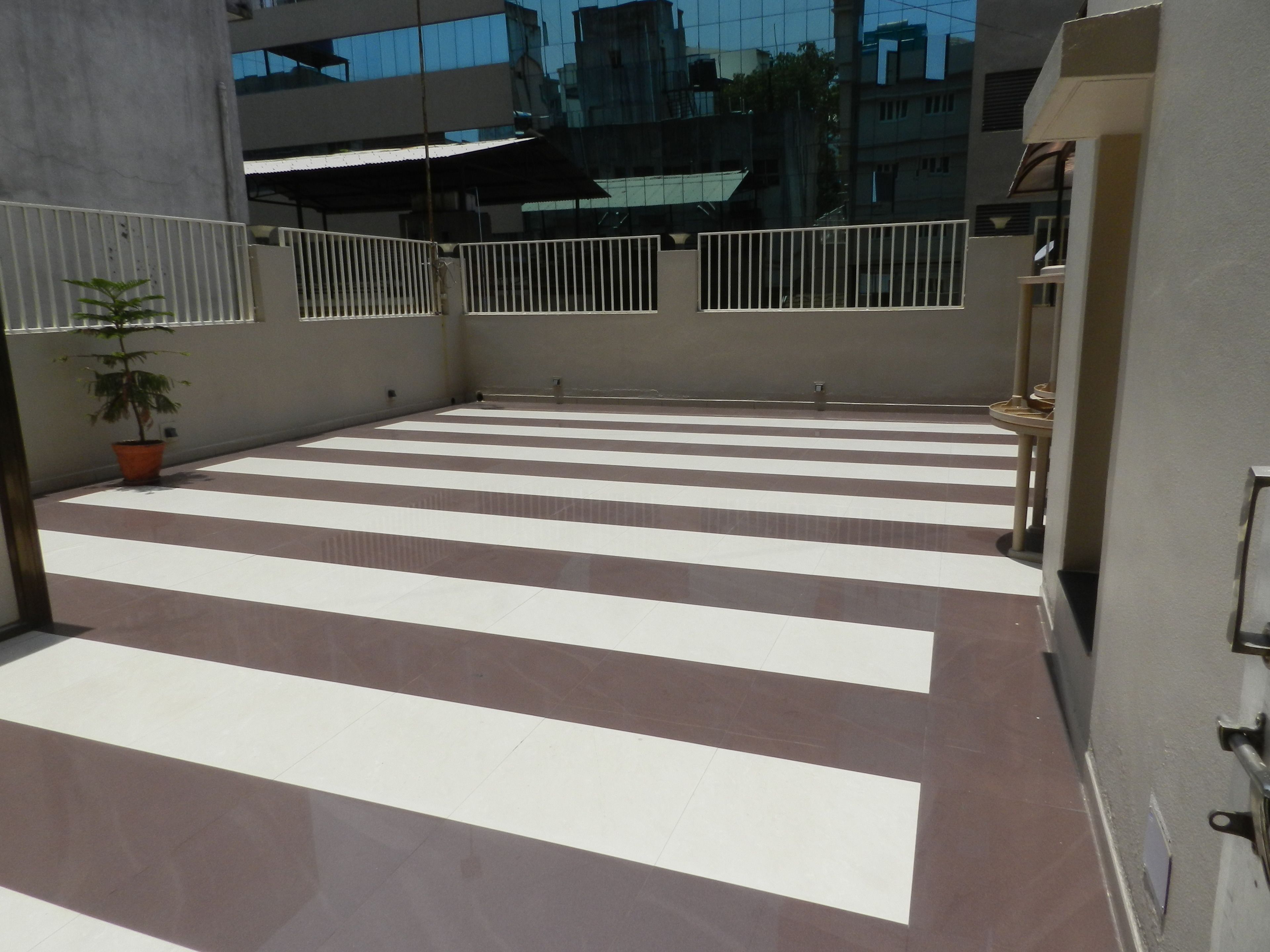 A spacious outdoor area with a tiled floor and a potted plant.