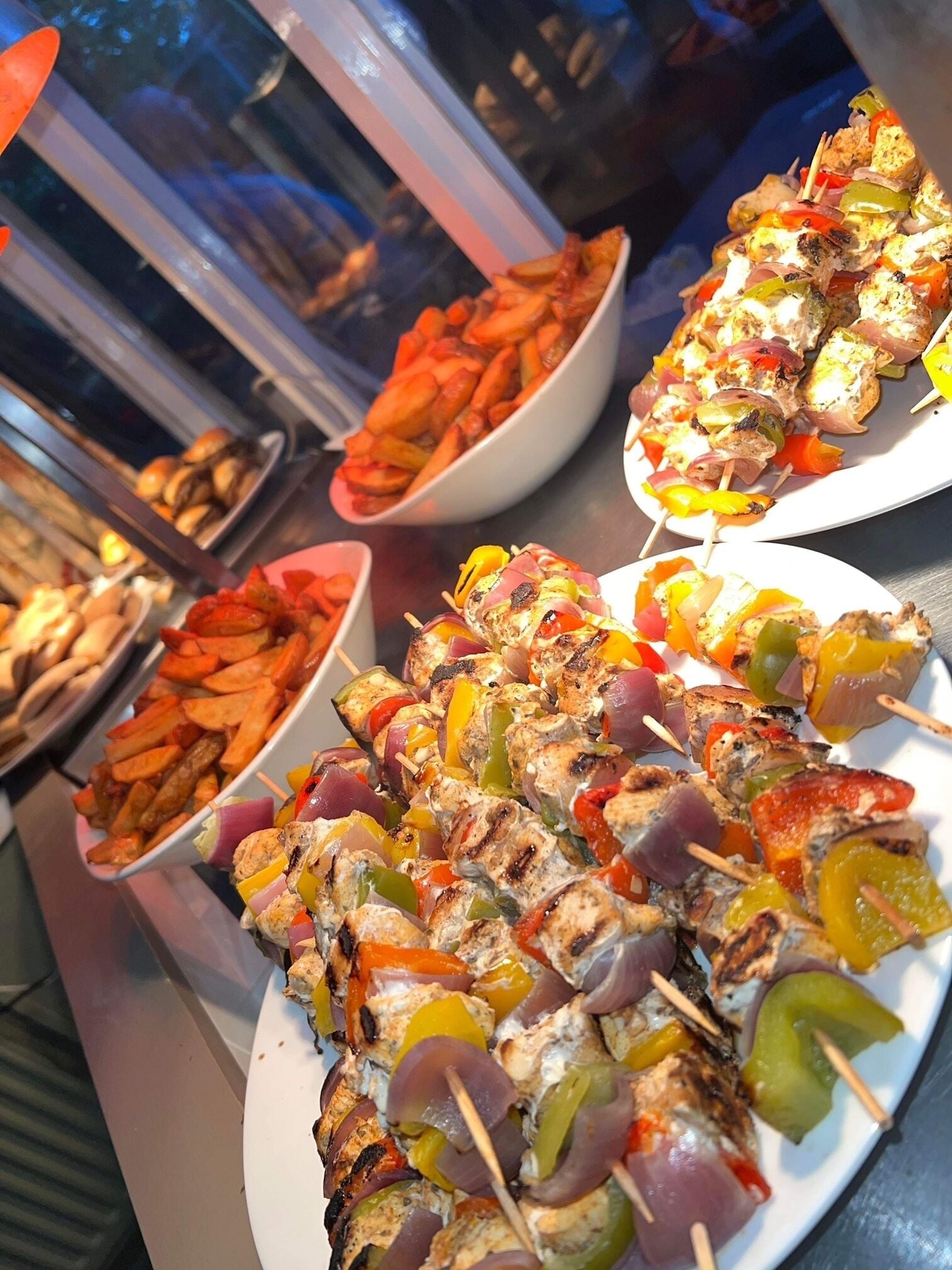 A buffet with skewers of grilled chicken and vegetables.