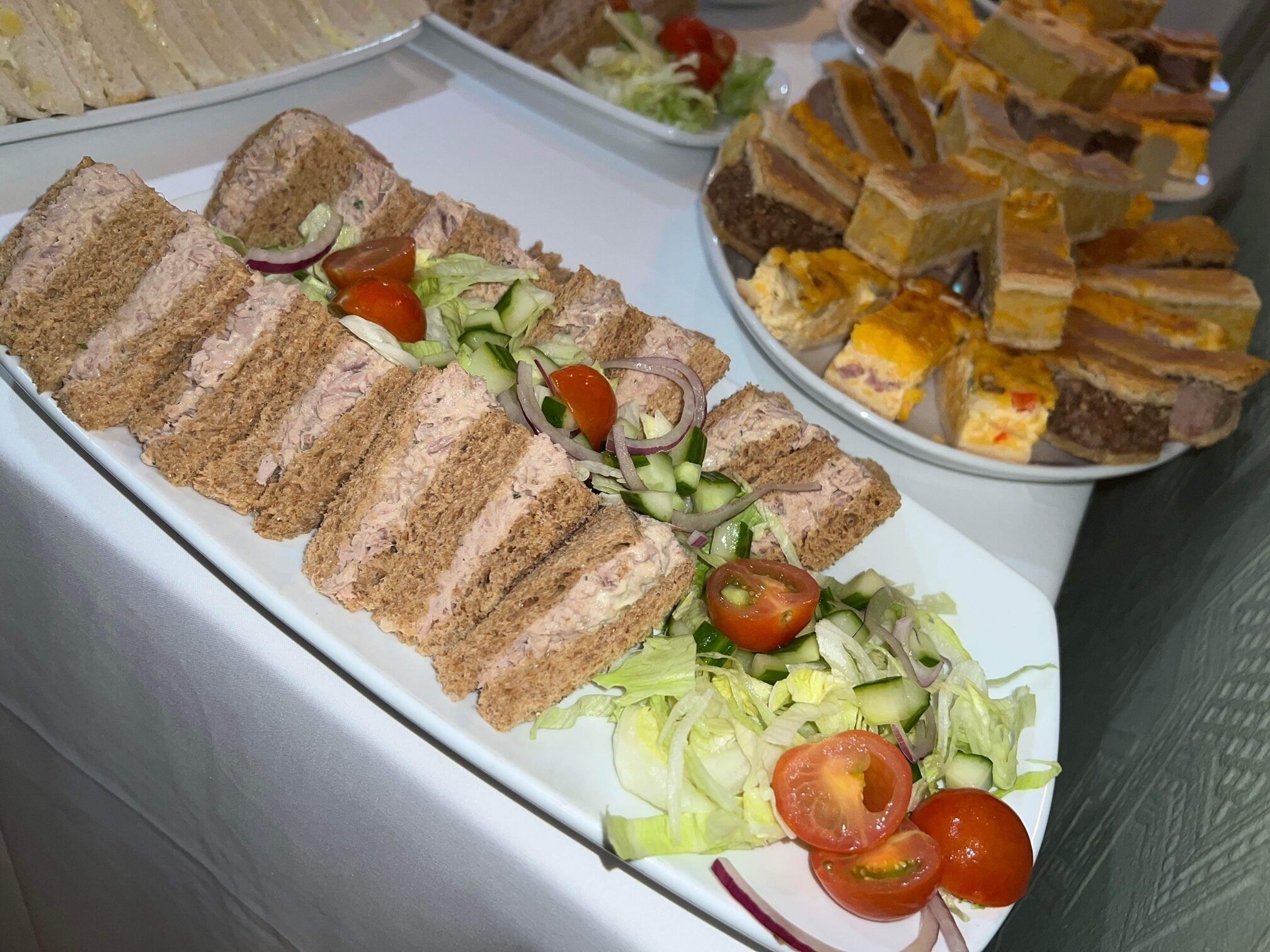 Una mesa de buffet con diversos alimentos, como sándwiches, ensaladas y otros platos.