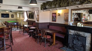 A pub with a pool table, billiards, and a bar area with a mirror and candles.