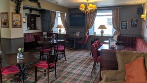 A cozy restaurant interior with red cushioned seating, a checkered floor, and a chandelier.
