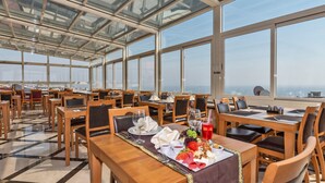 A restaurant with multiple tables and chairs, a glass ceiling, and a view of the cityscape. - Piya Sport Hotel (Istanbul)