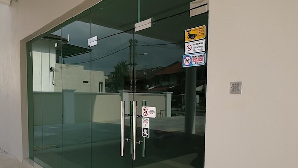 A modern building entrance with glass doors, a no smoking sign, and a no smoking sign for a specific area. - First Guest House Cheras (Cheras)