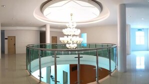 A spacious, modern hotel lobby with a glass railing and a central chandelier. - First Guest House Cheras (Cheras)