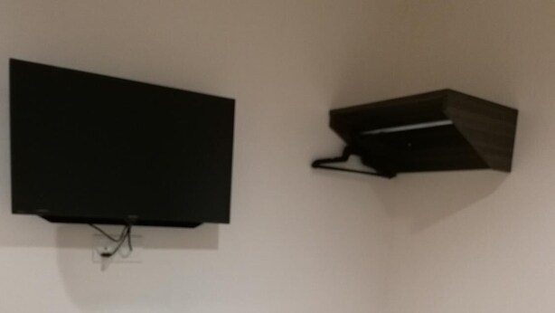 A room with a bed, a TV mounted on the wall, and a small trash bin. - First Guest House Cheras (Cheras)