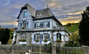 Ein zweistöckiges Haus mit einem steilen Satteldach, einer steinernen Fassade und mehreren Fenstern mit Fensterläden.