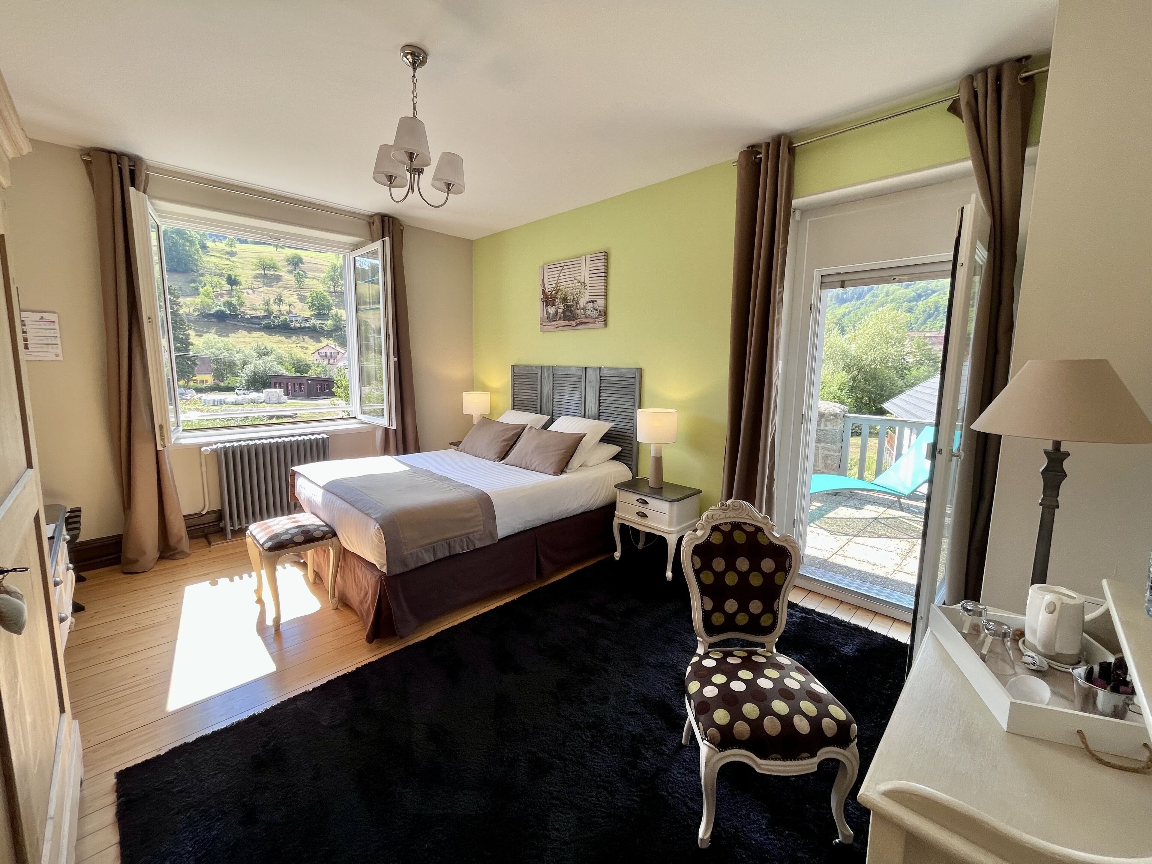 Een slaapkamer met een bed, nachtkastjes, een stoel, een raam en uitzicht op de omgeving.