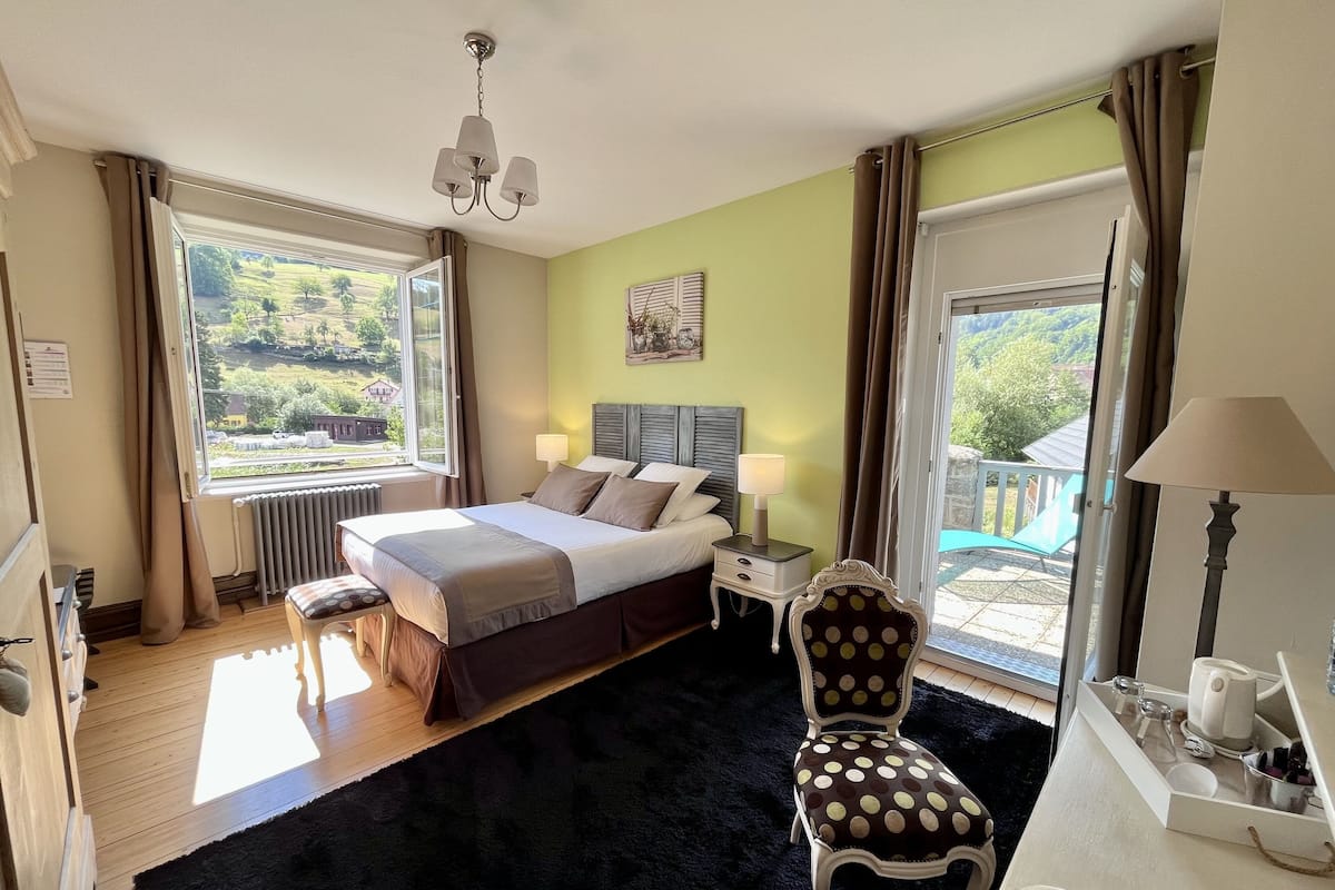 Een slaapkamer met een bed, nachtkastjes, een stoel, een raam en uitzicht op de omgeving.
