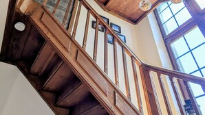 Un escalier en bois avec une rampe en verre, menant à un deuxième étage.