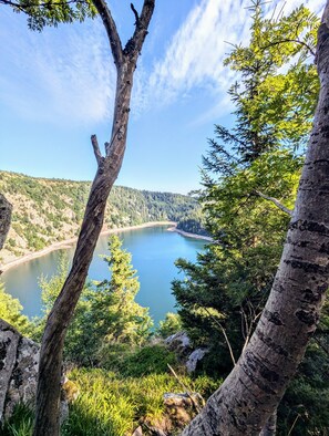 Un lac entouré de collines boisées, sous un ciel dégagé.