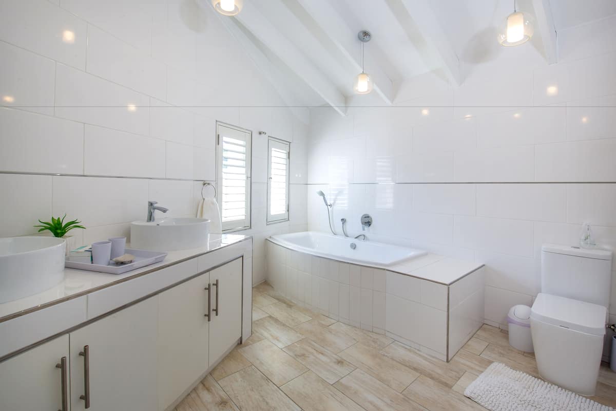 A modern bathroom with a large bathtub, a double sink, and a toilet.