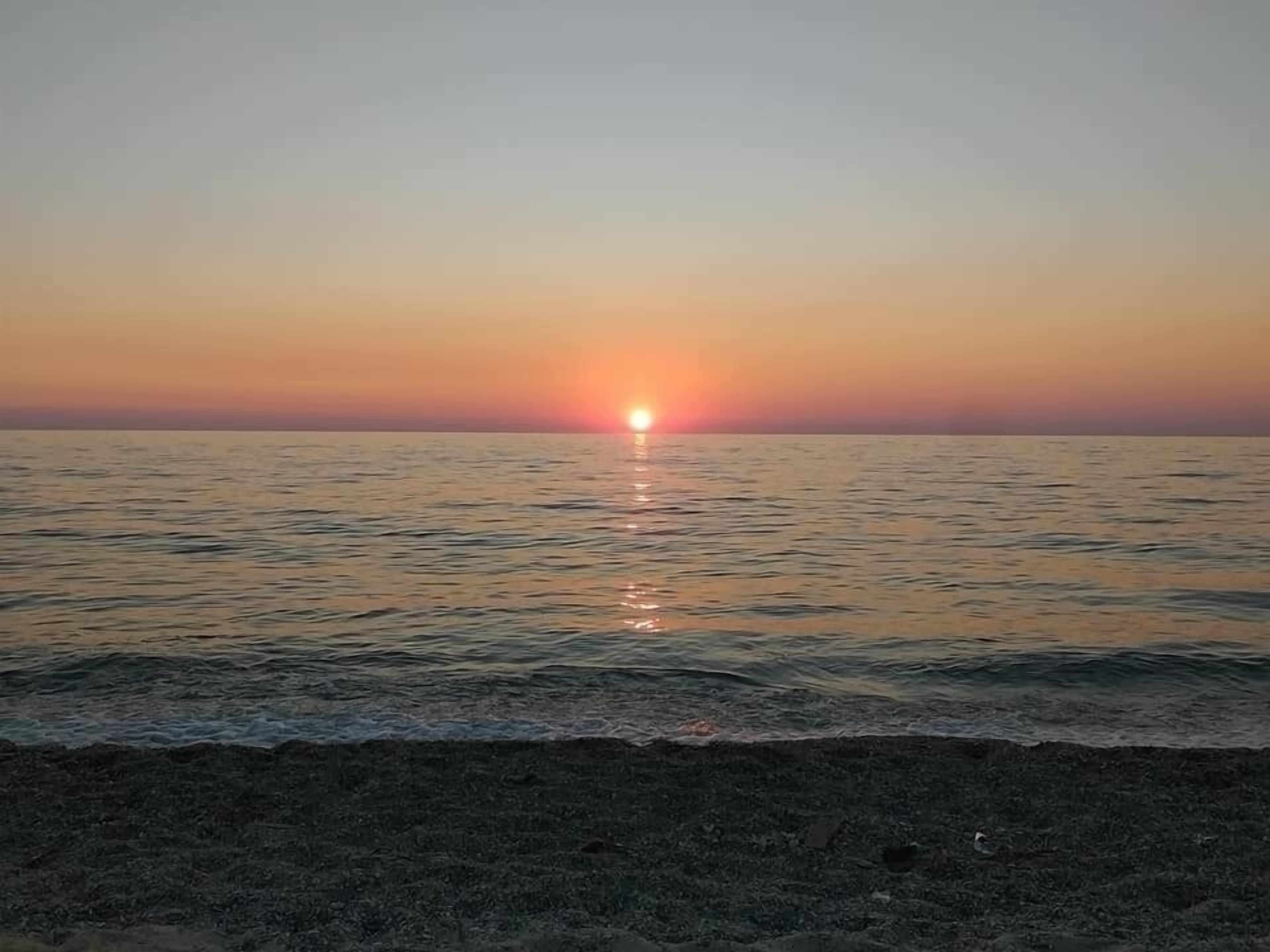 Une plage où le soleil se couche sur l’eau.