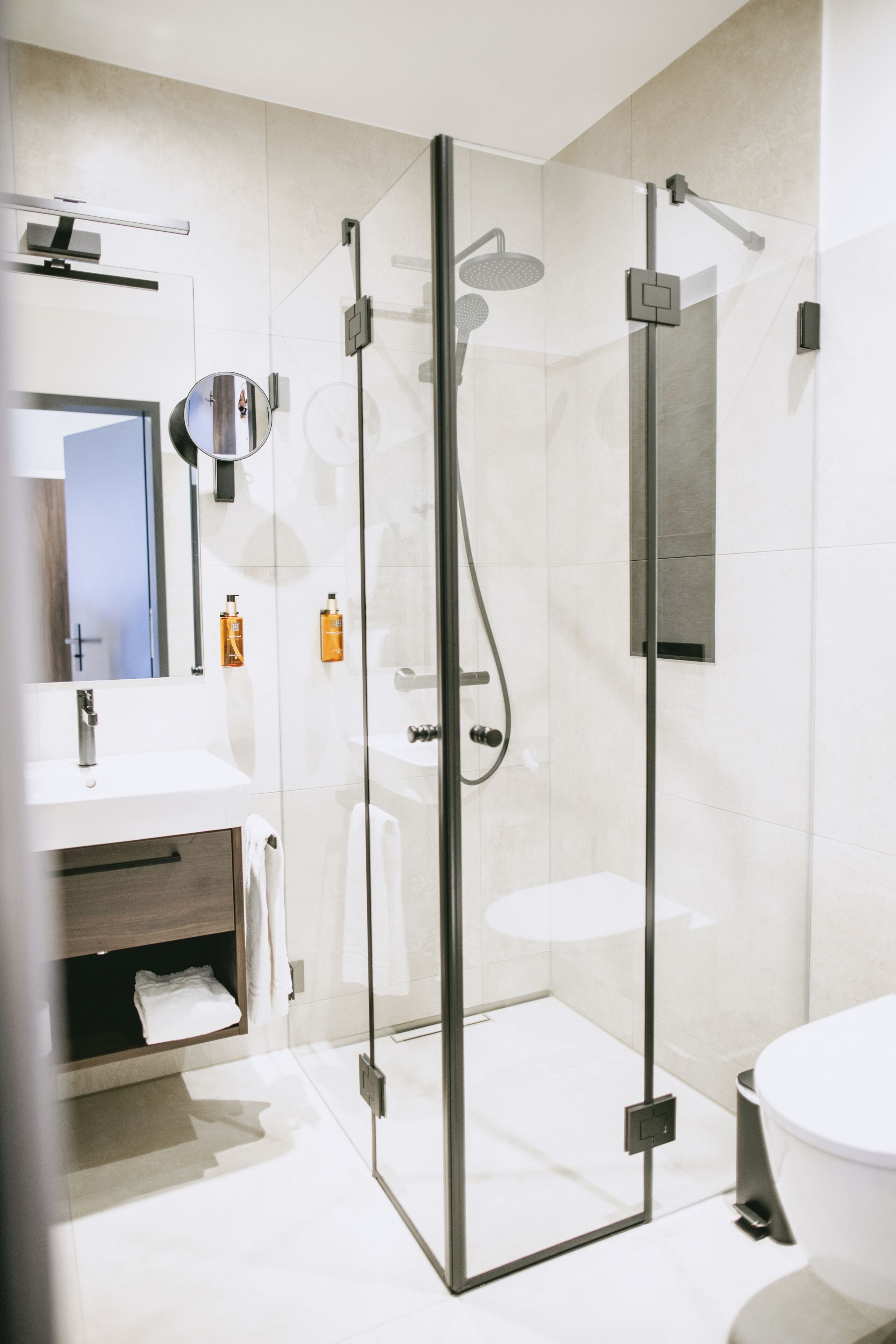 Un baño moderno con ducha de vidrio, lavamanos blanco y retrete.