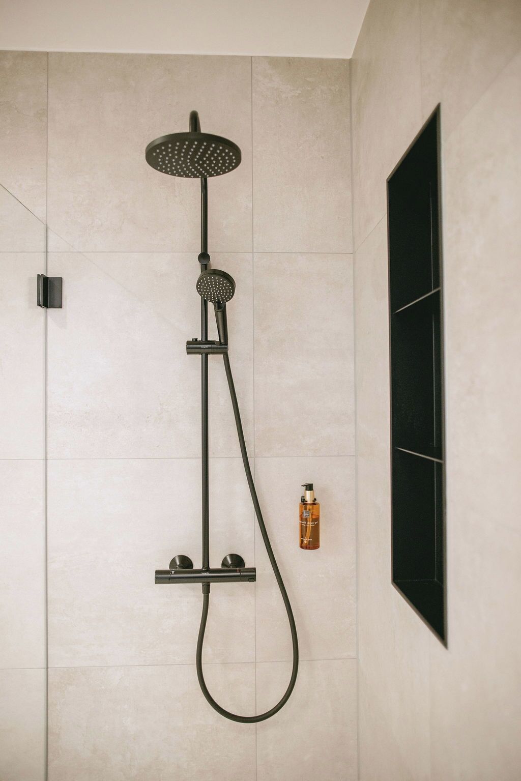 Une douche équipée d’un pommeau de douche à main et d’un accessoire de douche à effet pluie également à main.