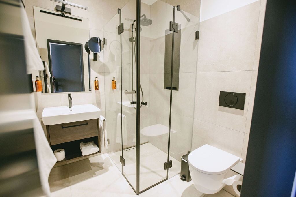 Ein modernes Badezimmer mit einer gläsernen Dusche, einem weißen Waschbecken und einer Toilette.