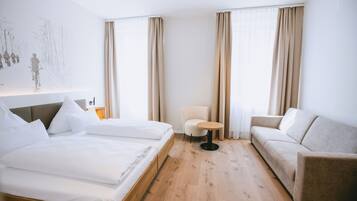 Una habitación de hotel con una cama, un sofá, una mesita redonda y una silla.