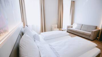 Une chambre d’hôtel avec un lit, un canapé, une chaise et une grande fenêtre.