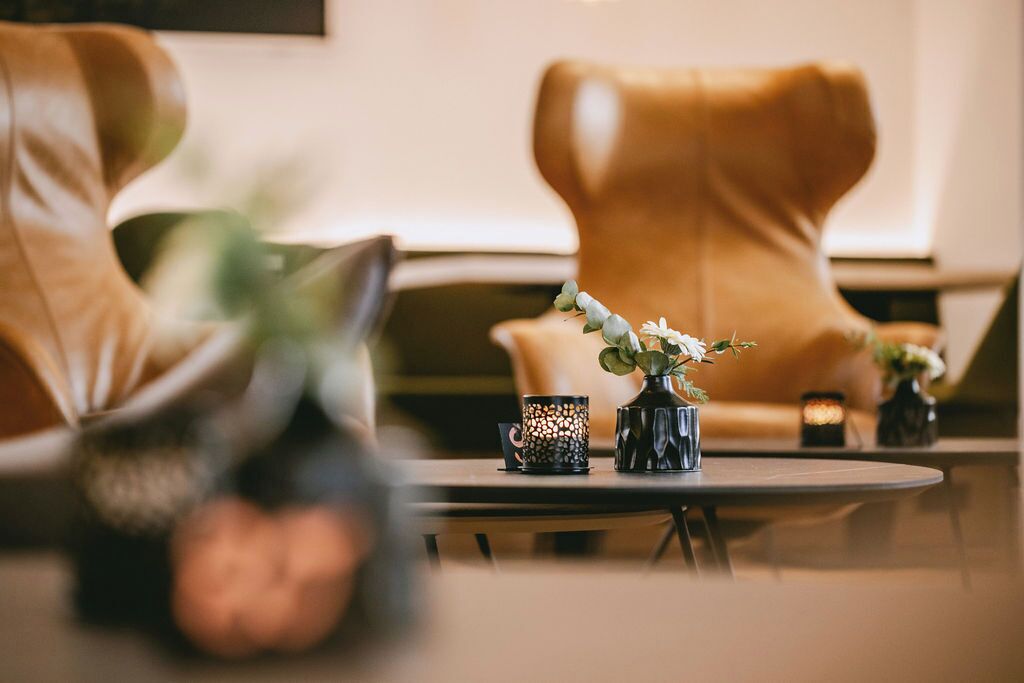 Ein Zimmer mit einem runden Tisch, zwei Vasen mit Pflanzen und einem Ledersessel.