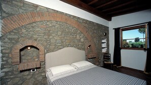 Ein Schlafzimmer mit Steinwand, einem Bett, einem Fenster und einem Kamin.