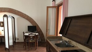 Eine Küche mit Spüle, Holdekor-Schränken, einem Esstisch mit Stühlen und einem Fernseher.