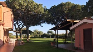 Ein Patio mit Pergola, Sitzgelegenheiten im Freien und einem Rasen.