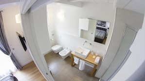 Een moderne badkamer met toilet, hygiëneschuimer en wastafel.