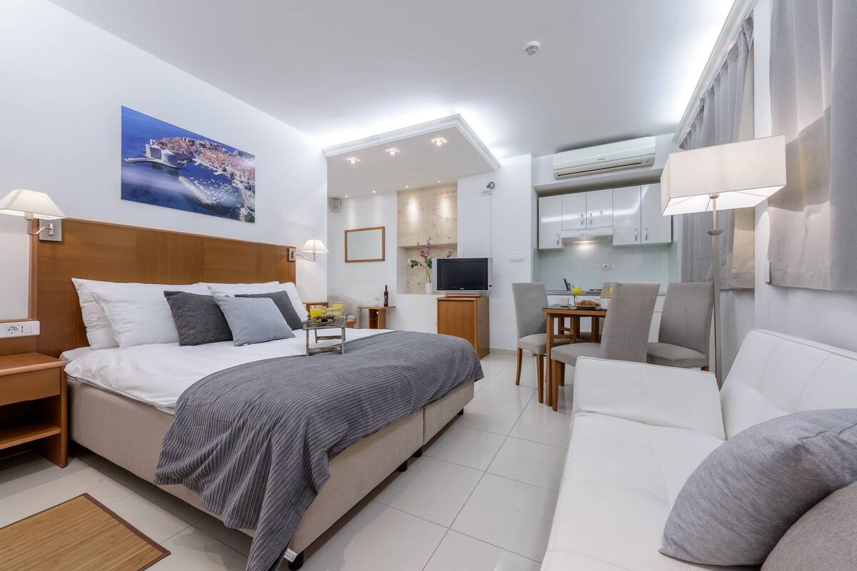 Une chambre d’hôtel moderne équipée d’un lit, d’un canapé, d’un coin repas et d’une cuisine.