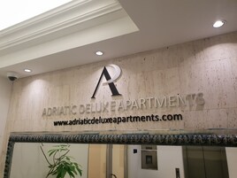 A sign for Adriatic Delux Apartments with a website URL.