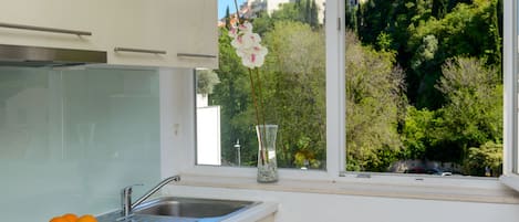Una cocina moderna con un lavamanos, un plato de naranjas y un jarrón con flores en el alféizar de la ventana.