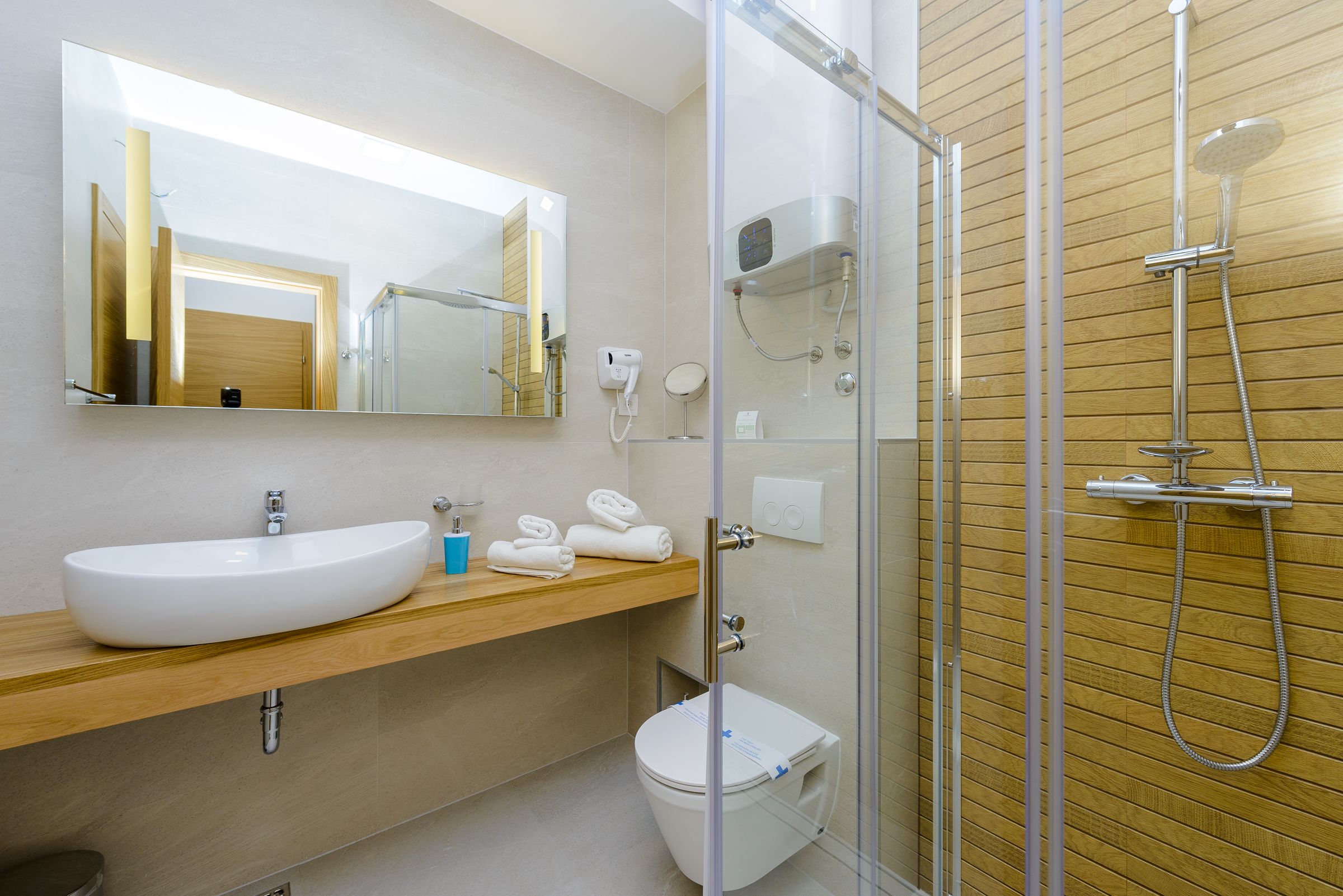 A modern bathroom with a large white sink, a glass-enclosed shower, and a wooden vanity.