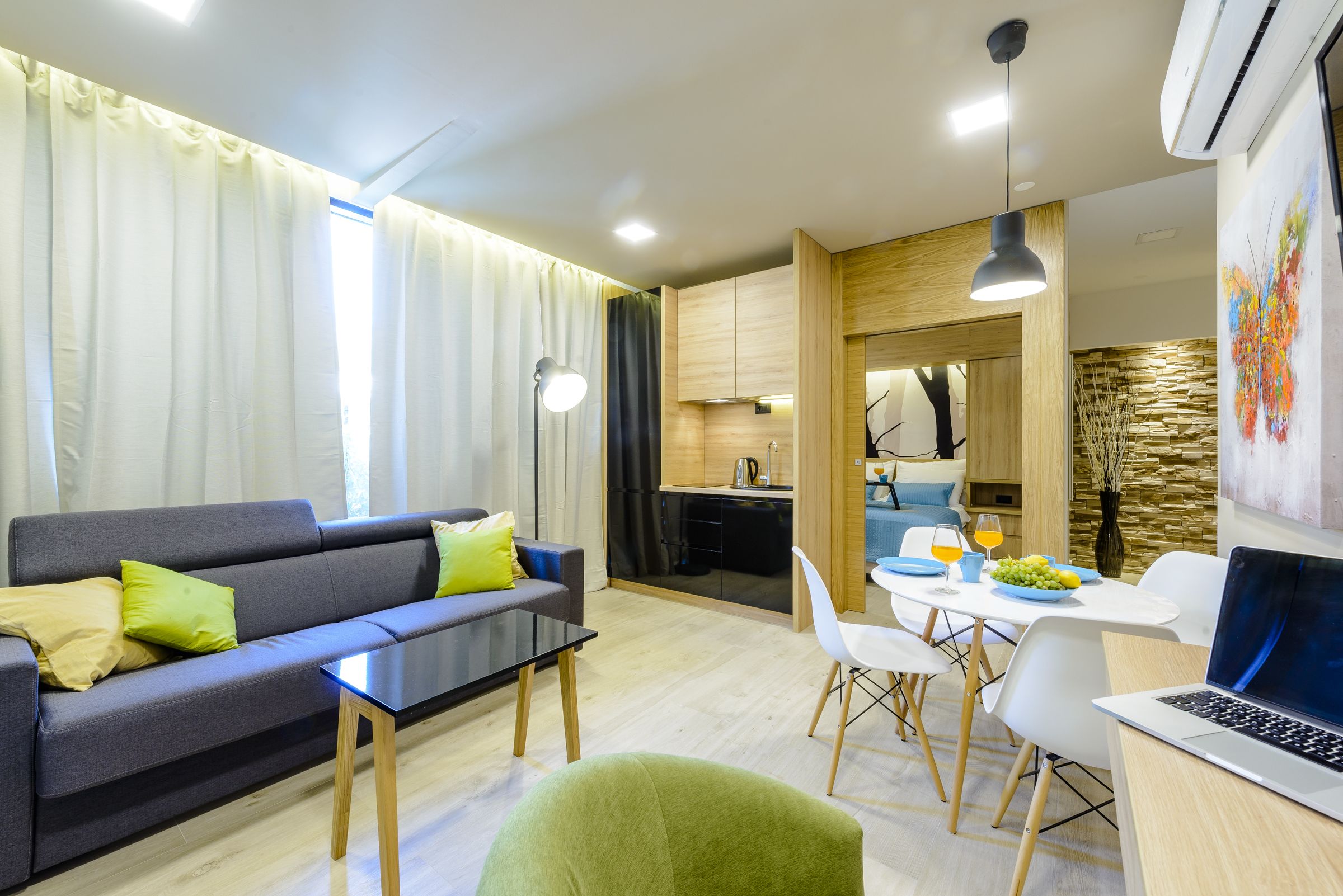 A modern living room with a sofa, a dining table, and a laptop.