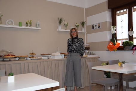 A room with a buffet table, chairs, and a person standing.