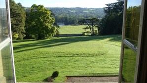 A view from a window overlooking a green field with trees and a distant landscape. - Château d'Ailly (Parigny)