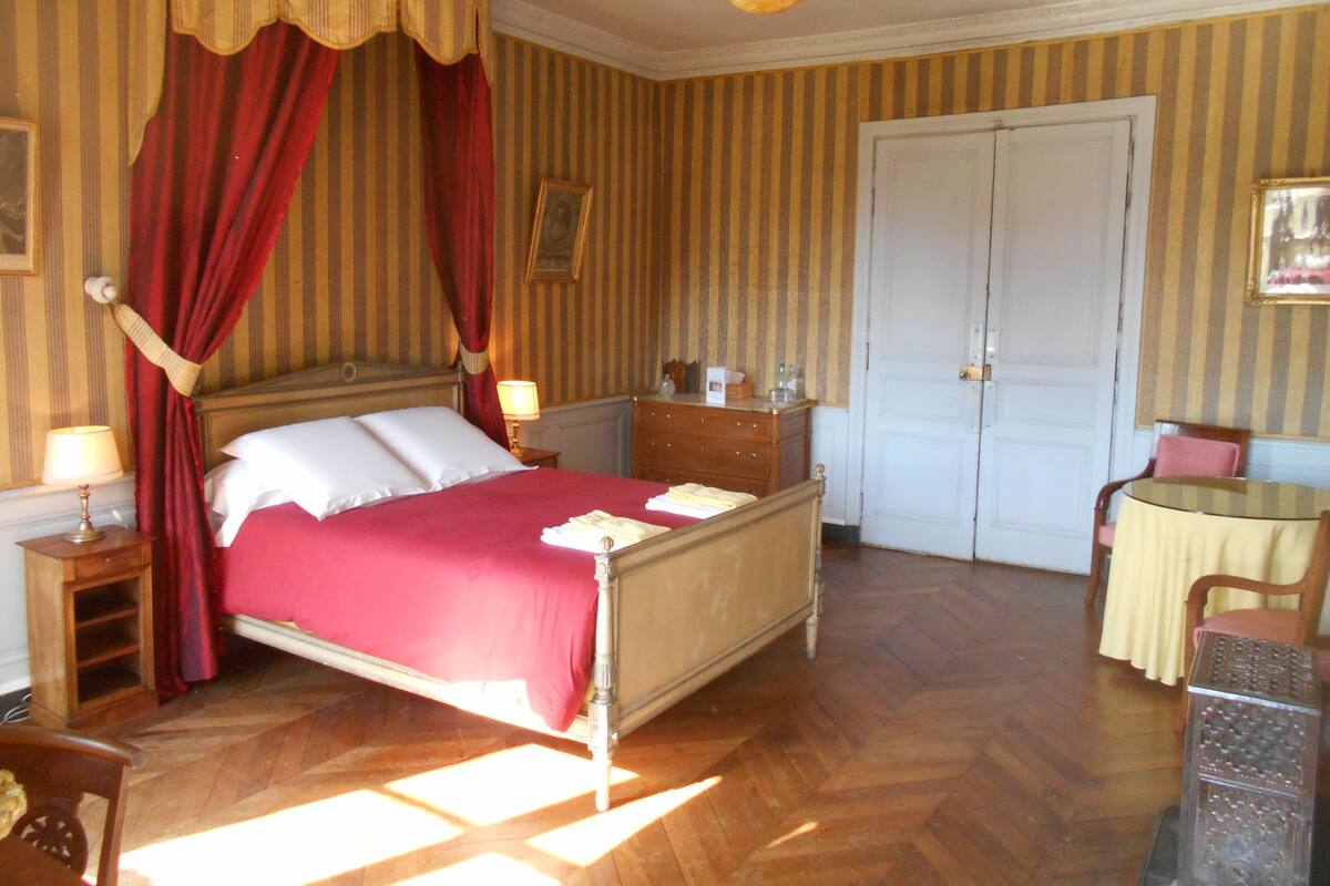 A room with a bed, a dresser, a table, and a door.