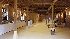 A spacious hall with high ceilings and exposed wooden beams, featuring a long table set for dining and several chairs. - Château d'Ailly (Parigny)